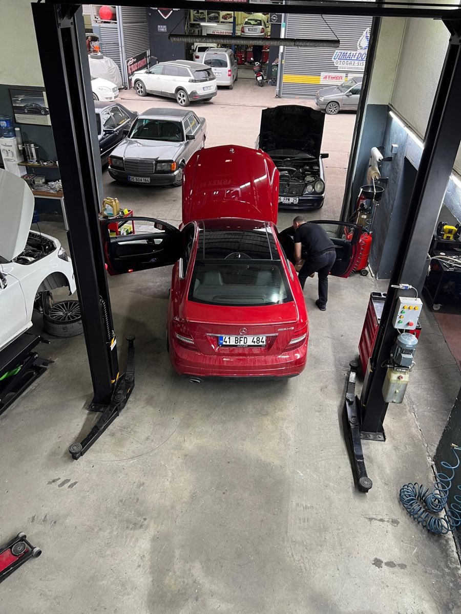 Asmer Mercedes servisi atölyesinde lift üzerinde kırmızı Mercedes ve çalışan usta, Gölcük Kocaeli